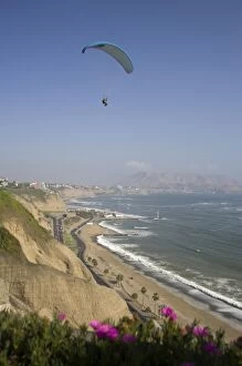 Parasailor soars over cliffs and ocean in Miraflores neighborhood, Lima, Peru
