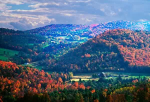 On a partly cloudy day in the fall, the sun has illuminated some hills more than