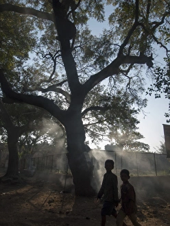 South Asia Prints: Pedestrians pass burning leaves in Bijapur, Karntaaka, India