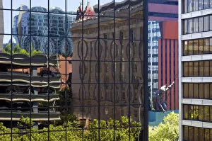 Portlandia sculpture seen between buildings reflected in buildings in downtown Portland