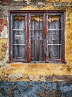 Peeling Prints: Portugal, Costa Nova. Very old wooden window with shutters on a colorful wall of peeling paint
