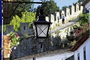 Portugal, Obidos. Iron streetlamp and 14th century crenellated walls that surround hill town