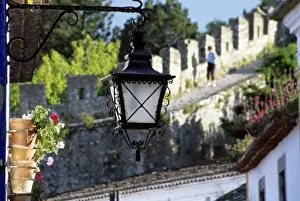 Portugal Prints: Portugal, Obidos. Iron streetlamp and 14th century crenellated walls that surround hill town