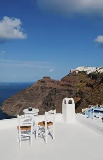 Postcard scene of two lonely chairs on terrace with table ready for tourists in Santorini