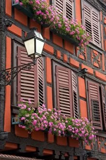 Red building with shuttered windows and flower boxes in the village of Ribeauville, Eastern France