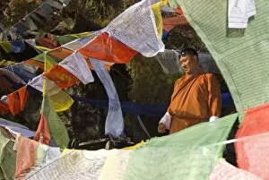 Images Dated 31st October 2006: Rimson stands on bridge at Membartsho(burning lake) surrounded by prayer flags, Tang Valley