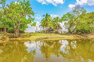 Murray Mccallum Prints: Sepik River, Papua New Guinea. Landscape view of a homestead and sandy banks reflected along the river