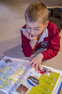 Reading Prints: Seven year old boy reading his world atlas book. (MR)