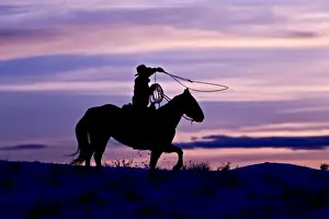 Western Scenic Prints: A silhouette of a cowboy on horses with the winter sky on The Hideout Ranch in Shell Wyoming