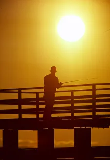 Fisherman Prints: Silhouette of man fishing from a pier