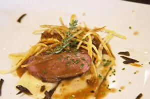 Slices of roast ducks breast placed on top of a ravioli with angle hair, thin