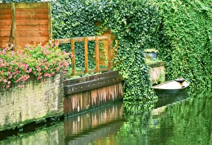 Small boat tied up in a canal next to a garden in Amsterdam