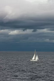 Images Dated 29th August 2008: A small sailboat makes its way through the waters of Puget Sound under dark storm clouds