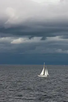 Weather Prints: A small sailboat makes its way through the waters of Puget Sound under dark storm clouds