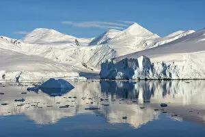 Snow covered island and iceberg with reflection in South Atlantic Ocean, Antarctica