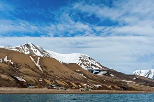 Longyearbyen Prints: Snow streaked cliffs rise behind a small settlement near Longyearbyen on the bay of Adventfjorden