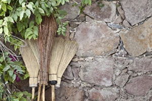 South America, Mexico, San Miguel de Allende. Brooms leaning against stone wall. Credit as