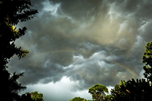 Florida Prints: Storm clouds approach in this photograph while a rainbow is illuminated by sunrays