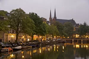 Images Dated 6th September 2007: Street lights reflect onto the canal at dusk with a lit bridge and De Krijtberg in