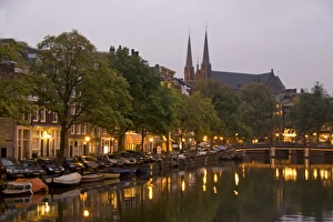 Images Dated 6th September 2007: Street lights reflect onto the canal at dusk with a lit bridge and De Krijtberg in