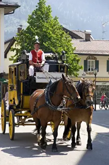 Stage Prints: Street scene with a horse drawn stage coach in the alpine village of Garmisch, Germany