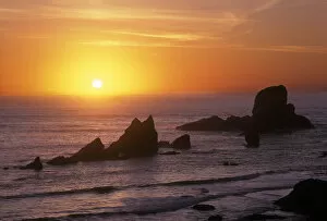 The sun ball sets in the orange sky and ocean at Ecola State Park, Oregon coast