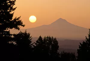 The sun hangs above Mt Hood, as viewed from Portland, Oregon