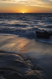 Sunray Prints: Sun setting on the Pacific Ocean with reflection of golden in the sand