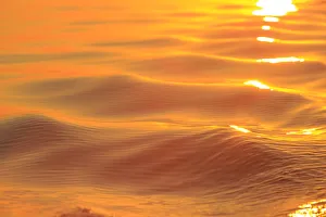 Sunset colors and patterns on small waves in water