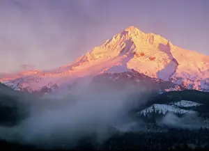 Sunset colors the slopes of Mt Hood, Oregon as clouds and fog sit in the valleys