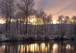 Sunset behind snow dusted trees reflecting in the Snoqualmie River, Washington
