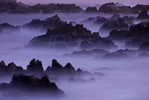 Surf pours over the California coastline at dusk