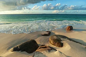 Away From It All Prints: Surf surging towards boulders buried in sand on a tropical beach