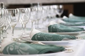 Table set in traditional style, white plates with golden decoration, white and green linen napkins