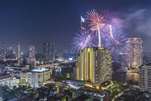 Cityscape Prints: Thailand, Bangkok. Riverside, high angle skyline view with fireworks at dusk