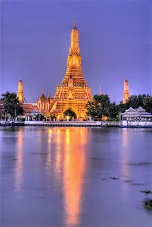 Wat Arun Prints: Thailand, Bangkok, Wat Arun. Ornate Buddhist temple reflects in river at dusk. Credit as