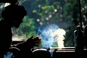 Images Dated 16th October 2006: Thailand, Doi Inthanon National Park, Young woman sits by steaming tea kettle at