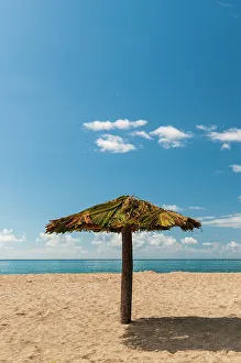 West Indies Prints: A tiki umbrella on a palm tree trunk on Pinney's white sand beach