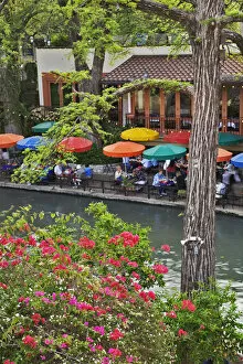 Tourists dining in outdoor cafe under colorful umbrellas on the famous River Walk
