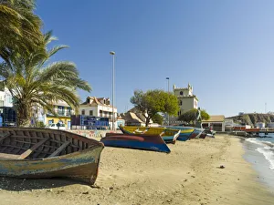 Traditional fishing boats on the beach of the harbor, landmark Torre de Belem in