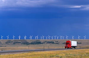 A truck traveling on the highway with a row of windmills in the background in Arlington