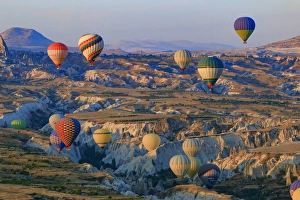 Turkey Gallery: Turkey, Anatolia, Cappadocia, Goreme. Hot air balloons flying above / among rock formations