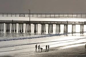 Images Dated 8th March 2015: US, CA, Avila Beach. Silhouetted beach walkers approach pier end of day