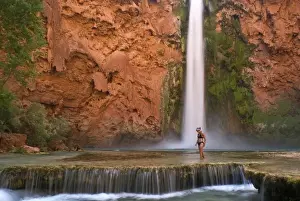 USA, Arizona, Havasu Canyon. A bikini-clad woman wades through the creek below thundering