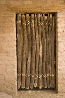 USA, Arizona, Tucson. Door made of wood poles and leather thongs in adobe wall at