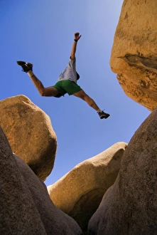 Images Dated 17th November 2012: USA, California, Joshua Tree National Park. A male hiker leaps across a boulder. (MR)