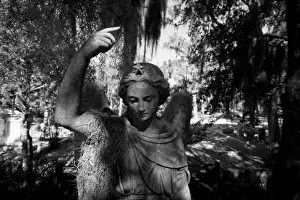 USA, Georgia, Savannah, Graveyard statue and trees draped in Spanish Moss inside