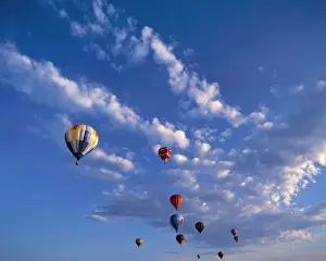 USA, Idaho, Teton Valley. Hot-air balloons seem in competition with the clouds above