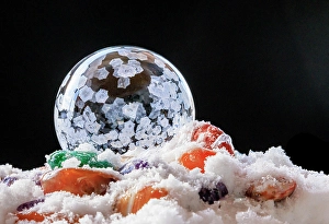 Images Dated 23rd January 2024: USA, Indiana, Carmel. Frozen soap bubble and polished stones in snow