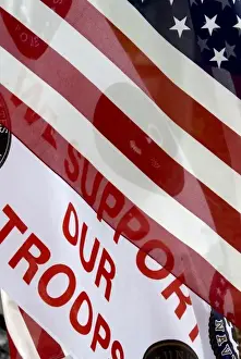 Banner Prints: USA, Indiana, Carmel. The message Support Our Troops partly seen through the American flag